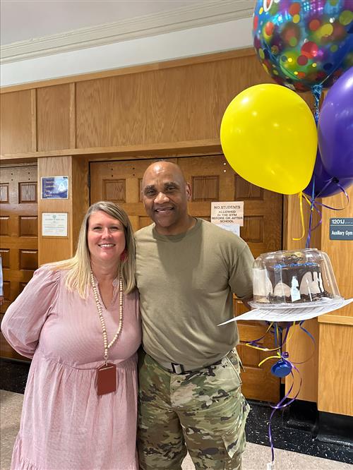 Mrs. Dilts and Master Sergeant McDuffie holding balloons and a cake.